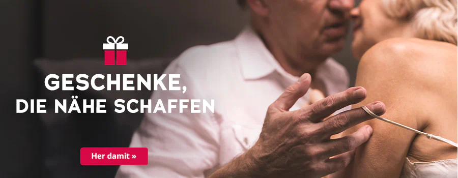 Das Bild zeigt eine Werbeanzeige, wo eine Frau und ein Mann dicht aneinander stehen. Der Mann trägt ein weißes Hemd und die Frau ein helles Oberteil mit dünnen Trägern. Die Köpfe sind dicht beieinander und der Mann macht mit seiner Hand den dünnen Träger der Frau an ihrer Schulter runter. Plakativ steht in großer, weißer Schrift "Geschenke, die Nähe schaffen“. Symbolisch ist ein Geschenk abgebildet. Unterhalb befindet sich ein rotfarbener Button mit der weißen Aufschrift „Her damit“.