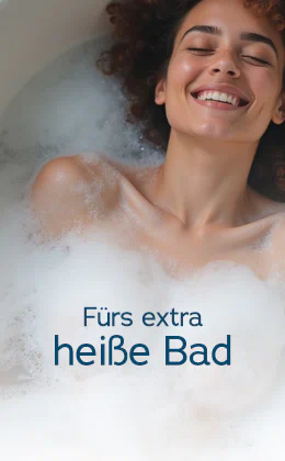 Eine lächelnde Frau mit lockigem braunem Haar liegt entspannt in einem weißen, mit Schaum gefüllten Bad. Großflächig steht „Fürs extra heiße Bad“. Unten zeigt ein roter Button den Text „Finde wasserfeste Toys »“.